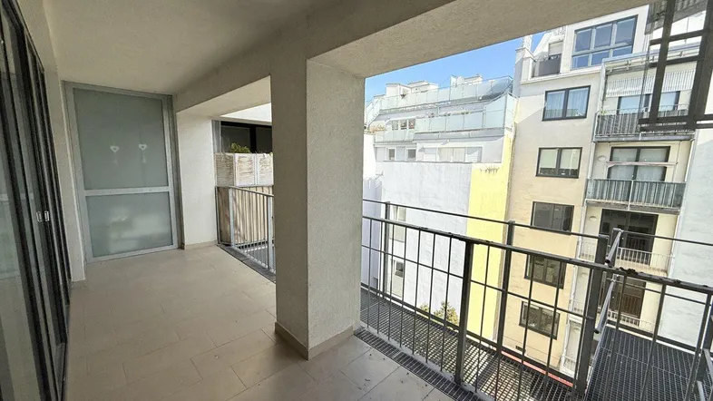 Langer Balkon mit Fliesenboden und Blick auf die umliegenden Gebäude.
