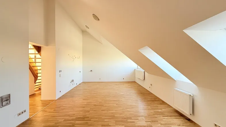 Geräumiger, heller Wohnbereich im Dachgeschoss mit Holzboden und Dachschrägen.