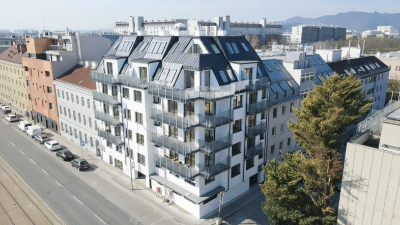 Moderne Wohnanlage mit mehreren Etagen und Dachgeschosswohnungen in städtischer Umgebung.