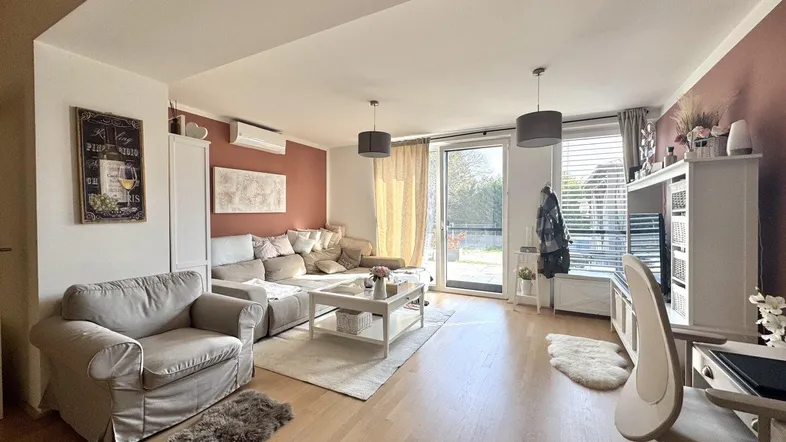 Helles Wohnzimmer mit beigefarbenem Sofa, Holzboden und Zugang zur Terrasse.