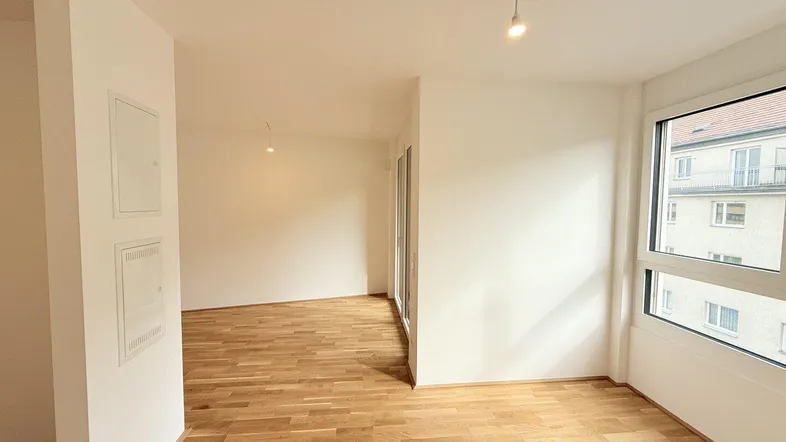 Heller, leerer Wohnbereich mit neuem Parkettboden und großen Fenstern, bereit zum Einzug.
