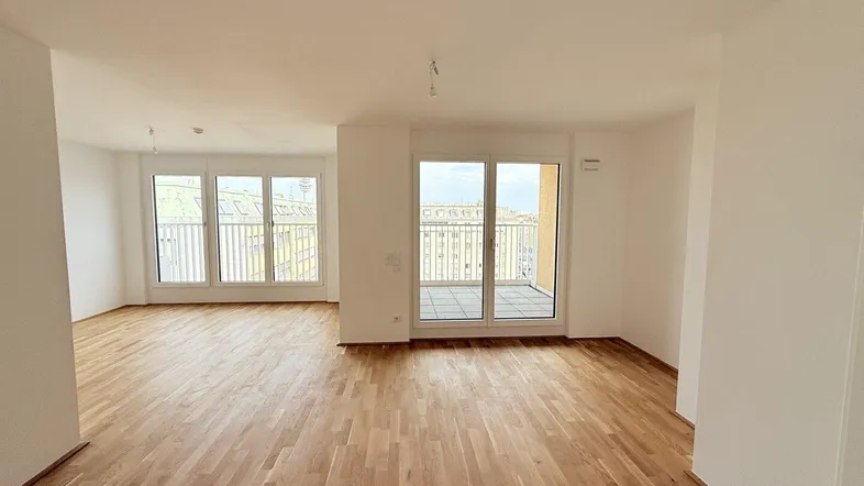 Helles, offenes Wohnzimmer mit neuem Parkettboden und Zugang zu einem Balkon.