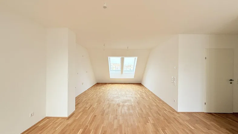 Geräumiger, heller Dachgeschossraum mit Parkettboden und Dachfenstern, ideal als Wohnzimmer nutzbar.