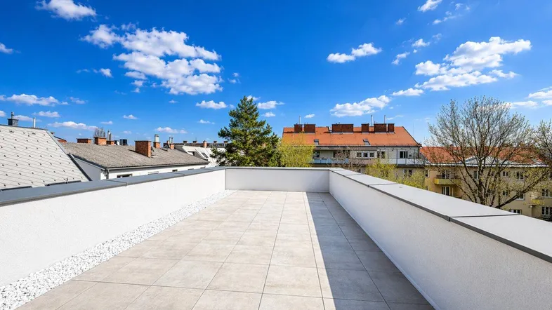 Geräumige Dachterrasse mit hellen Fliesen und weitem Blick über die Dächer der Stadt.