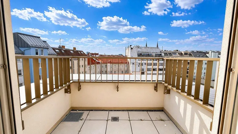 Geräumiger Balkon mit Fliesenboden und weitem Blick über die Stadt unter blauem Himmel.