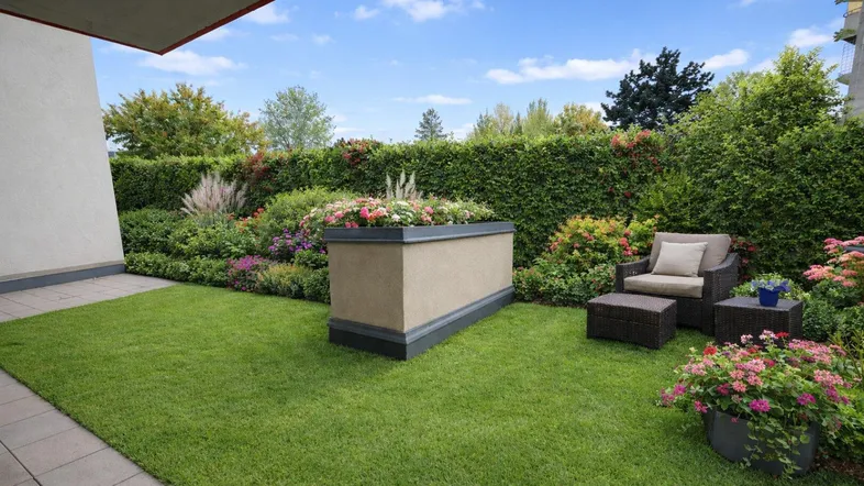 Schöner Gartenbereich mit Rasenfläche, Hecke und gemütlicher Sitzgelegenheit im Freien.