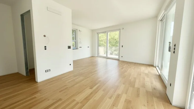 Helles, unmöbliertes Wohnzimmer mit großen Schiebetüren und hellem Holzparkettboden.