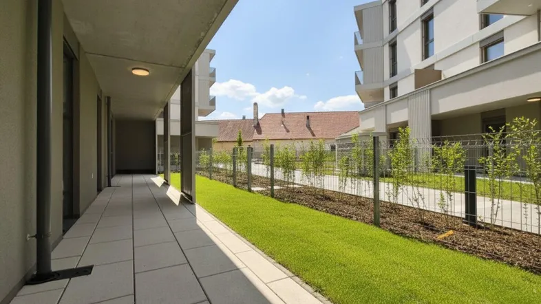 Moderner Gebäudekomplex mit gepflastertem Gehweg und Grünflächen unter blauem Himmel.