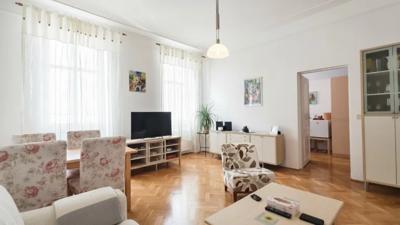 Helles Wohn- und Esszimmer mit Fischgrätparkett, hohen Decken und großen Fenstern.