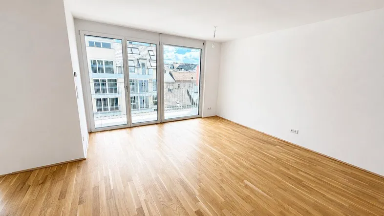 Helles Wohnzimmer mit Eichenparkett und großen Fenstern, die Zugang zu einem Balkon bieten.