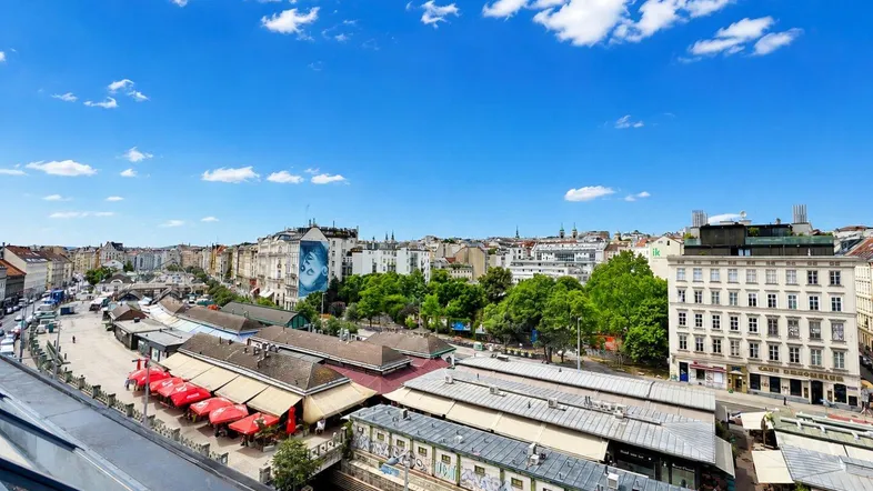 Panoramablick über die Stadt mit Marktständen und historischen Gebäuden unter blauem Himmel.