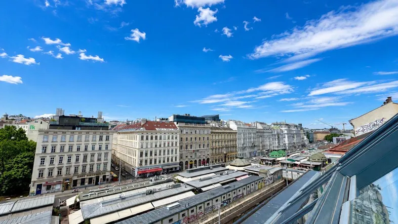 Weitläufiger Blick über die Dächer der Stadt mit blauem Himmel und Wolken.