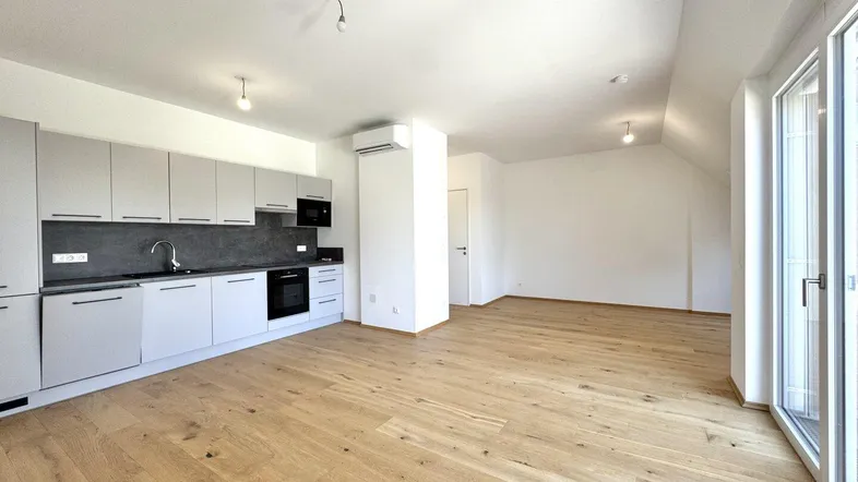 Helle, offene Wohnküche mit moderner Einbauküche, Holzboden und viel Tageslicht.