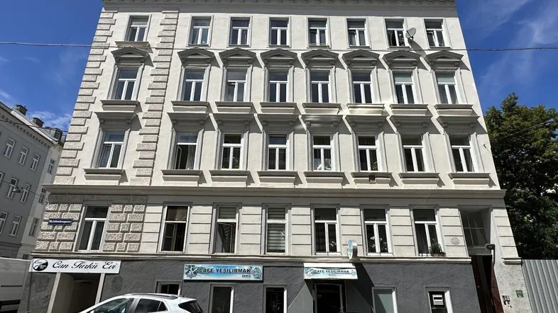 Historisches Mehrfamilienhaus mit klassischer Fassade und vielen Fenstern in urbaner Umgebung.