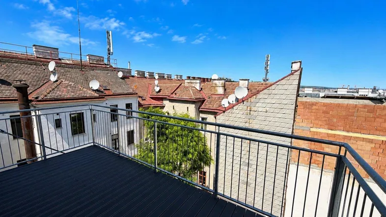 Geräumiger Balkon mit modernem Bodenbelag und weitem Blick über die Dächer der Stadt.