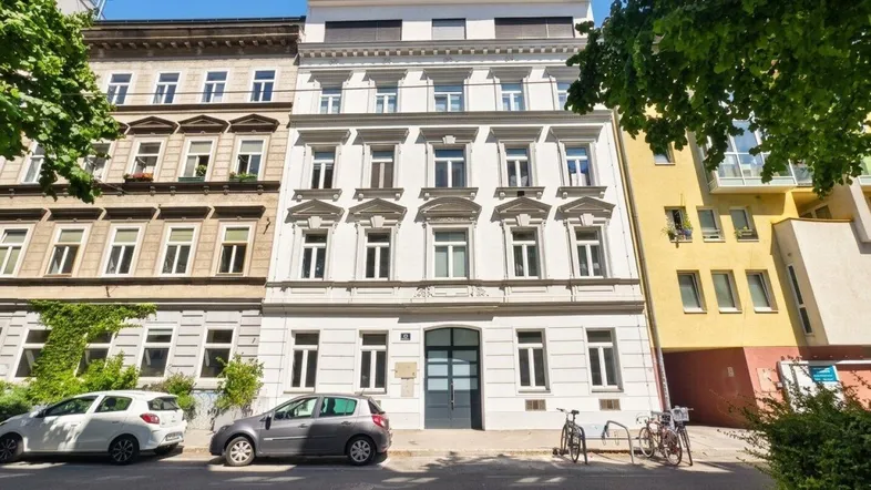 Historische Fassade eines Mehrfamilienhauses mit modernen Akzenten und Straßenblick.