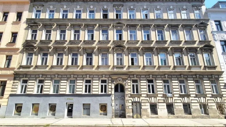 Historisches Mehrfamilienhaus mit klassischer Fassade und vielen Fenstern in städtischer Umgebung.