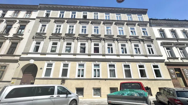 Klassisches Mehrfamilienhaus mit vielen Fenstern und traditioneller Architektur in städtischer Umgebung.