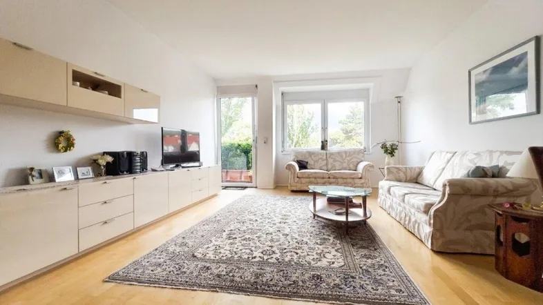 Helles Wohnzimmer mit Parkettboden, langer Schrankwand und Zugang zur Terrasse.