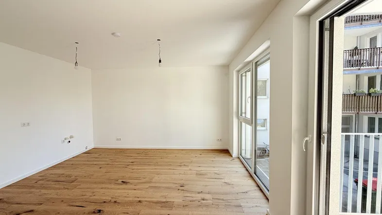 Helles, leeres Zimmer mit Holzboden und Zugang zu einem Balkon, bereit zur individuellen Gestaltung.