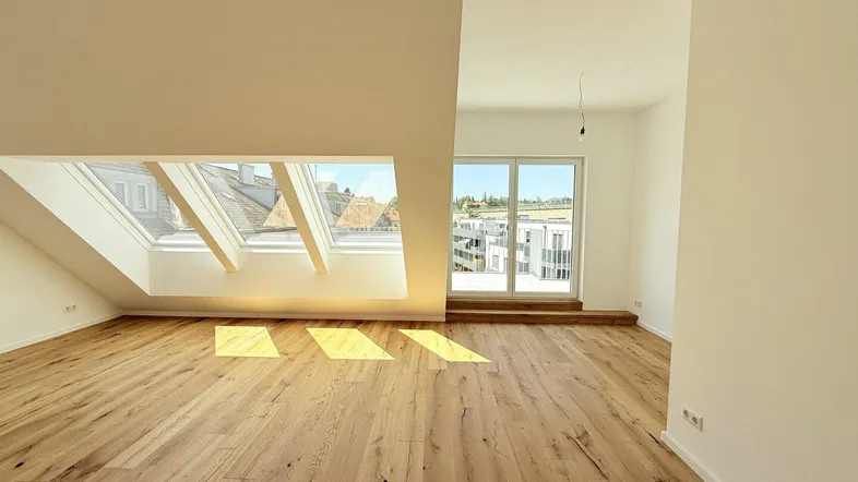 Helles Dachgeschosszimmer mit Holzboden und großen Dachfenstern, bietet viel Tageslicht und weite Ausblicke.