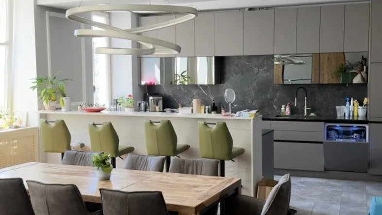 Moderne offene Küche mit Kücheninsel, Essbereich und dunklem Holzboden.