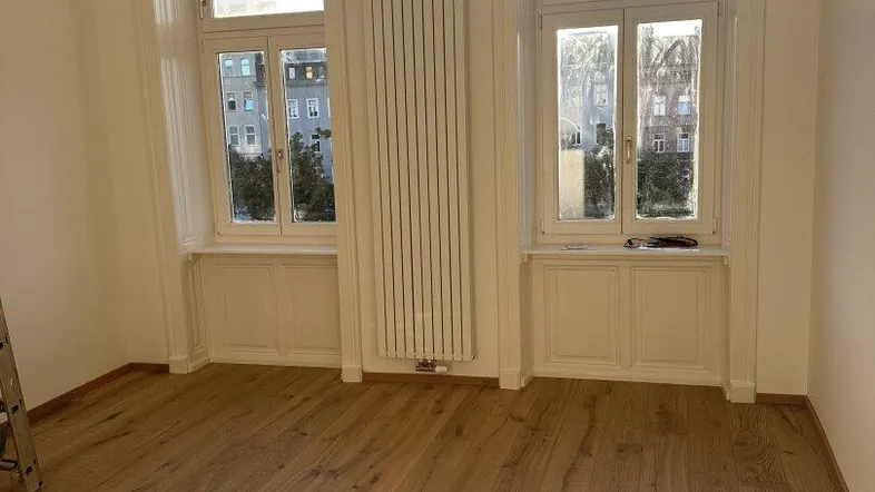 Helles Zimmer mit neuem Parkettboden und hohen Fenstern, bereit zur individuellen Gestaltung.