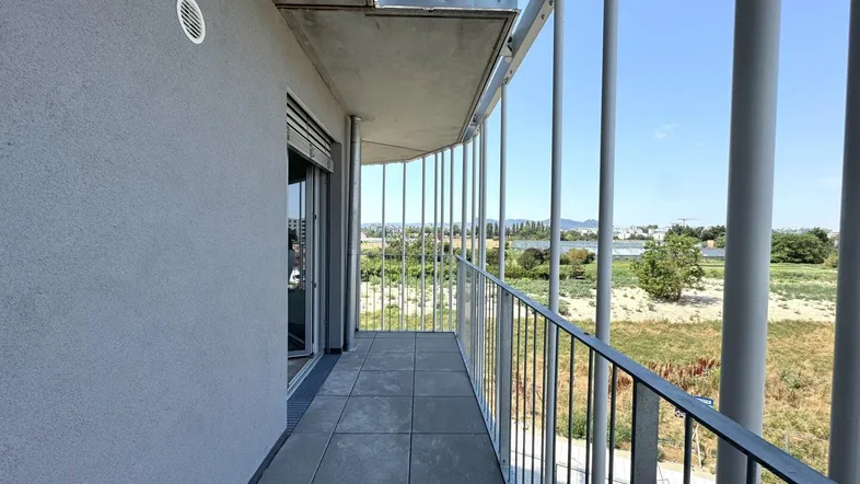 Geräumiger Balkon mit Fliesenboden und weitem Blick über die Landschaft und die Stadt.