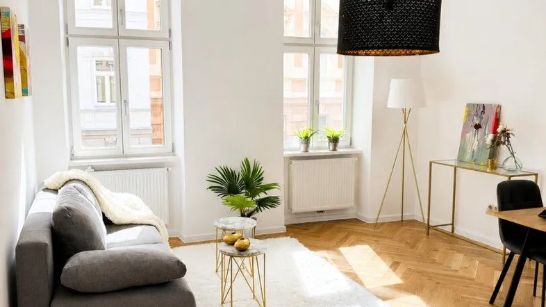 Helles Wohnzimmer mit Fischgrätparkett, großem Fenster und moderner Einrichtung, die zum Entspannen einlädt.