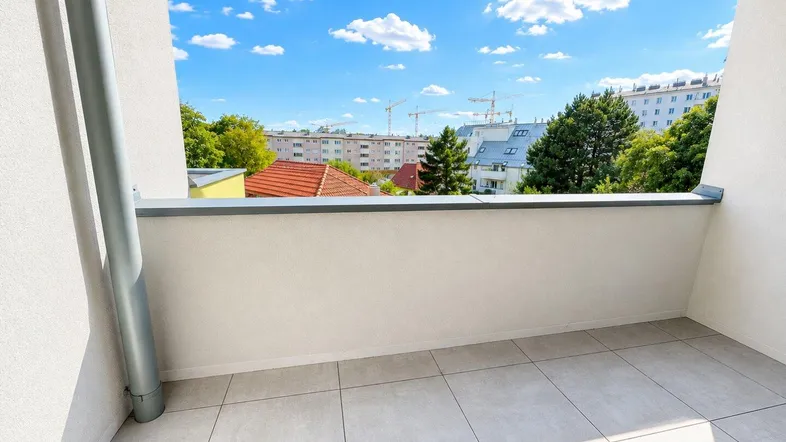 Geräumiger Balkon mit Fliesenboden und Blick auf die umliegende Bebauung und Bäume.