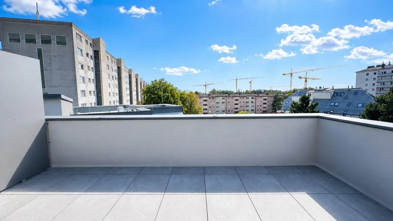 Geräumige Dachterrasse mit hellen Fliesen und weitem Blick über die Stadt bei Sonnenschein.