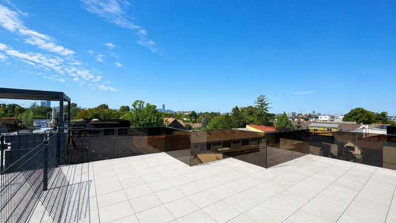 Geräumige Dachterrasse mit hellen Fliesen, moderner Glasbrüstung und weitem Blick über die Stadt.