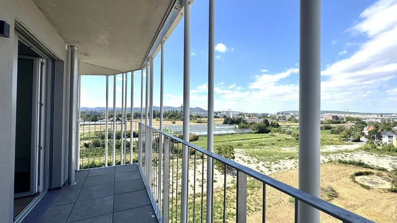 Geräumiger Balkon mit Fliesenboden und weitem Blick über die Landschaft und die Stadt.