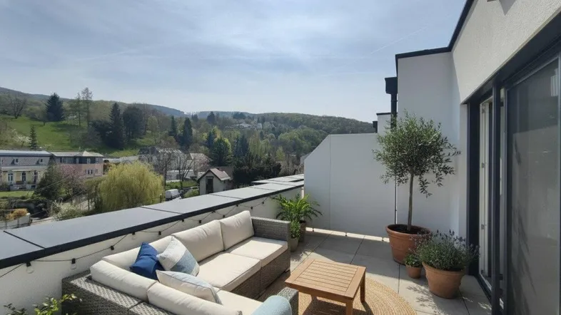 Große, sonnige Dachterrasse mit bequemen Loungemöbeln und weitem Blick über das Tal.