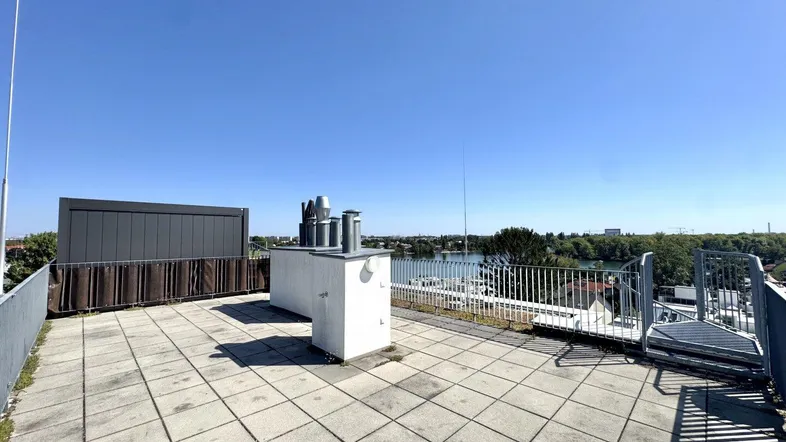 Große Dachterrasse mit Fliesenboden und weitem Blick auf den See und die Umgebung.