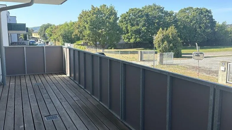 Geräumiger Balkon mit Holzboden und Blick ins Grüne, ideal für entspannte Stunden im Freien.
