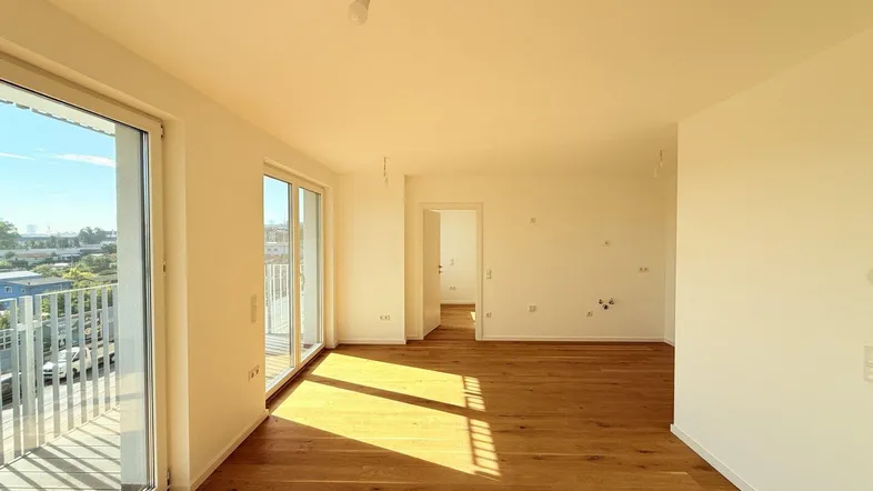 Helles Wohnzimmer mit Eichenparkett, großen Fenstern und Zugang zu einem Balkon.