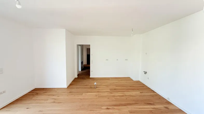 Heller, leerer Raum mit neuem Holzparkettboden und weißen Wänden.