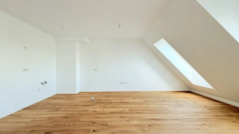 Helles Dachgeschosszimmer mit Holzboden und schrägen Wänden, bereit für individuelle Gestaltung.