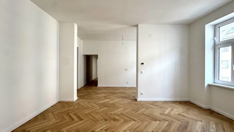 Helles, leeres Zimmer mit Fischgrätparkett und hohen Decken, bereit zur individuellen Gestaltung.