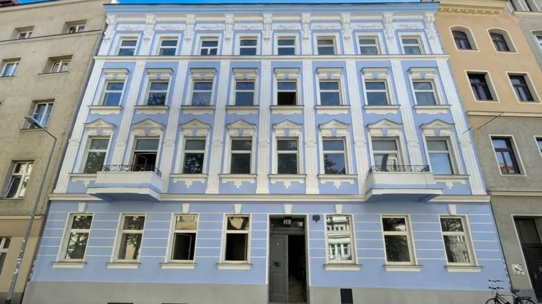 Historisches Gebäude mit hellblauer Fassade und aufwendigen Stuckverzierungen an den Fenstern.