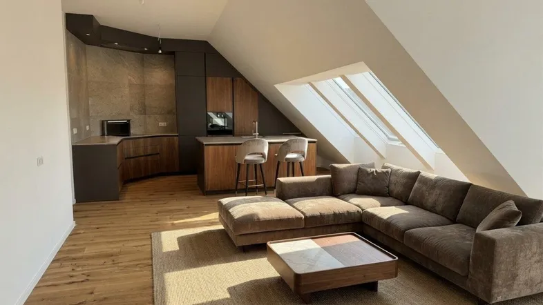 Modernes Dachgeschoss-Apartment mit offener Küche, Wohnbereich und großen Dachfenstern.