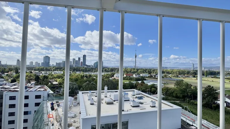 Panoramablick von einem Balkon auf die Stadtlandschaft mit Hochhäusern und weitem Himmel.