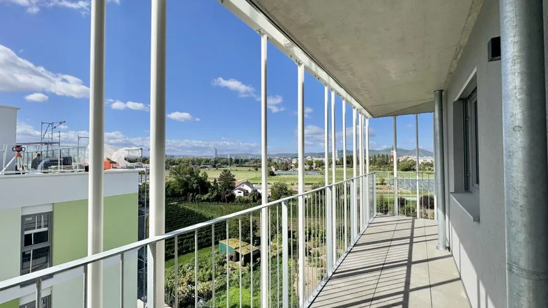 Heller Balkon mit weitem Blick über die Landschaft und die umliegenden Gebäude.
