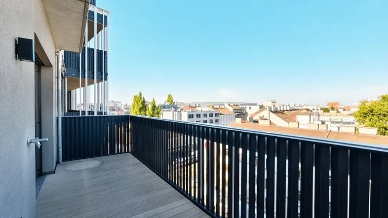 Geräumiger Balkon mit Holzboden und weitem Blick über die Stadtlandschaft.