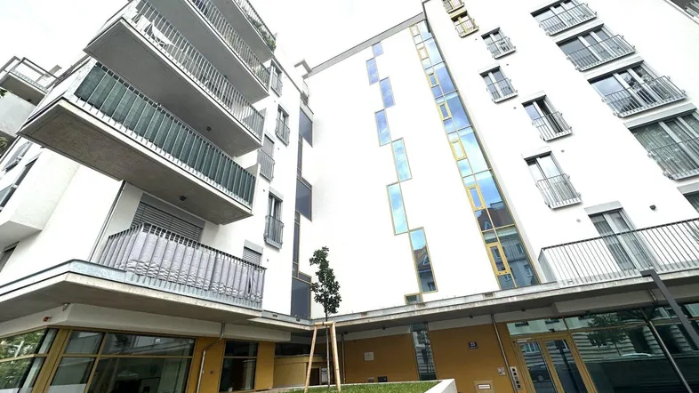 Moderne Wohnhausfassade mit Balkonen und großen Fenstern, von unten fotografiert.
