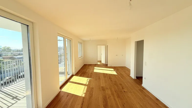 Helles, geräumiges Zimmer mit Holzboden und Zugang zu einem Balkon, durchflutet von Sonnenlicht.
