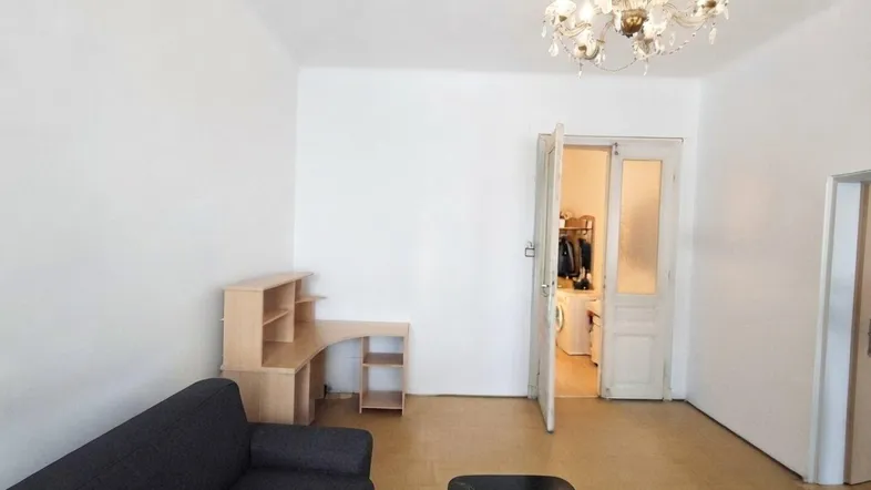Geräumiges Wohnzimmer mit Sofa, Schreibtisch und Kronleuchter, angrenzend an einen Hauswirtschaftsbereich.