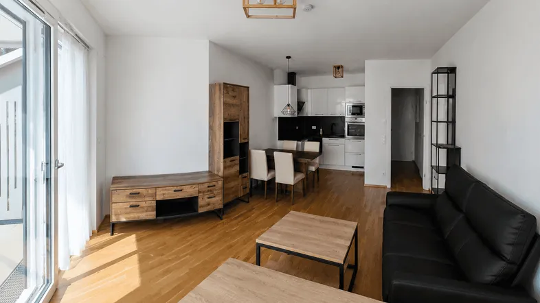 Heller offener Wohn- und Essbereich mit integrierter Küche und Zugang zum Balkon.