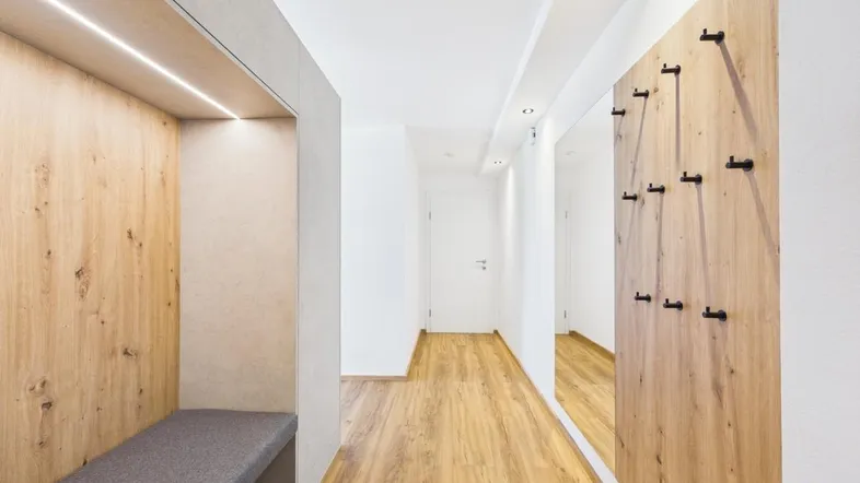 Heller Flur mit integrierter Sitzgelegenheit und Garderobe, die zu weiteren Räumen führt.